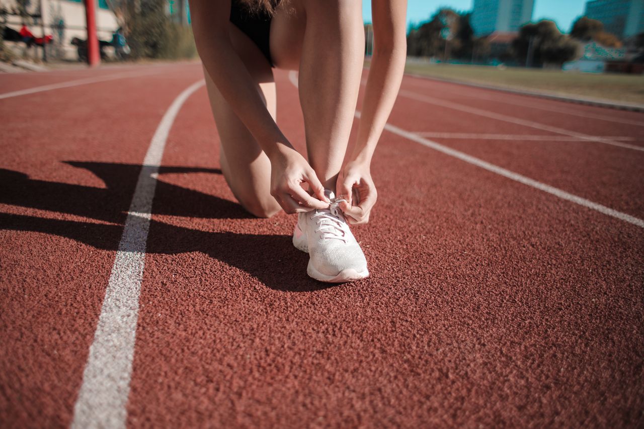 Mastering the First Impression: Your intriguing post title goes here Close-up of a woman tying her shoes on a running track, ready to sprint.